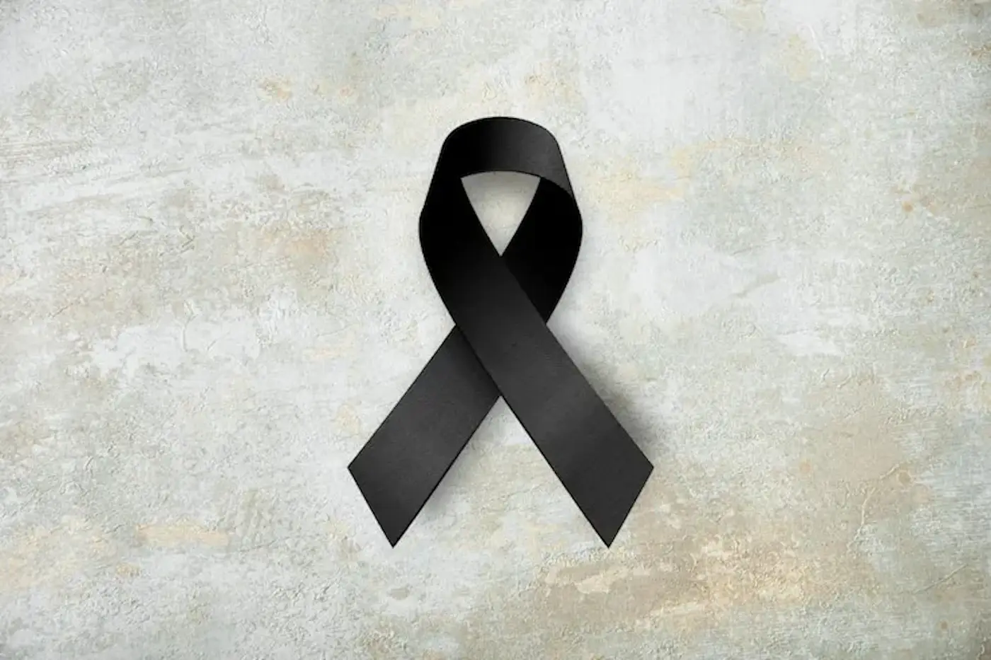 Nastro nero su uno sfondo grigio chiaro, simbolo di lutto e commemorazione.