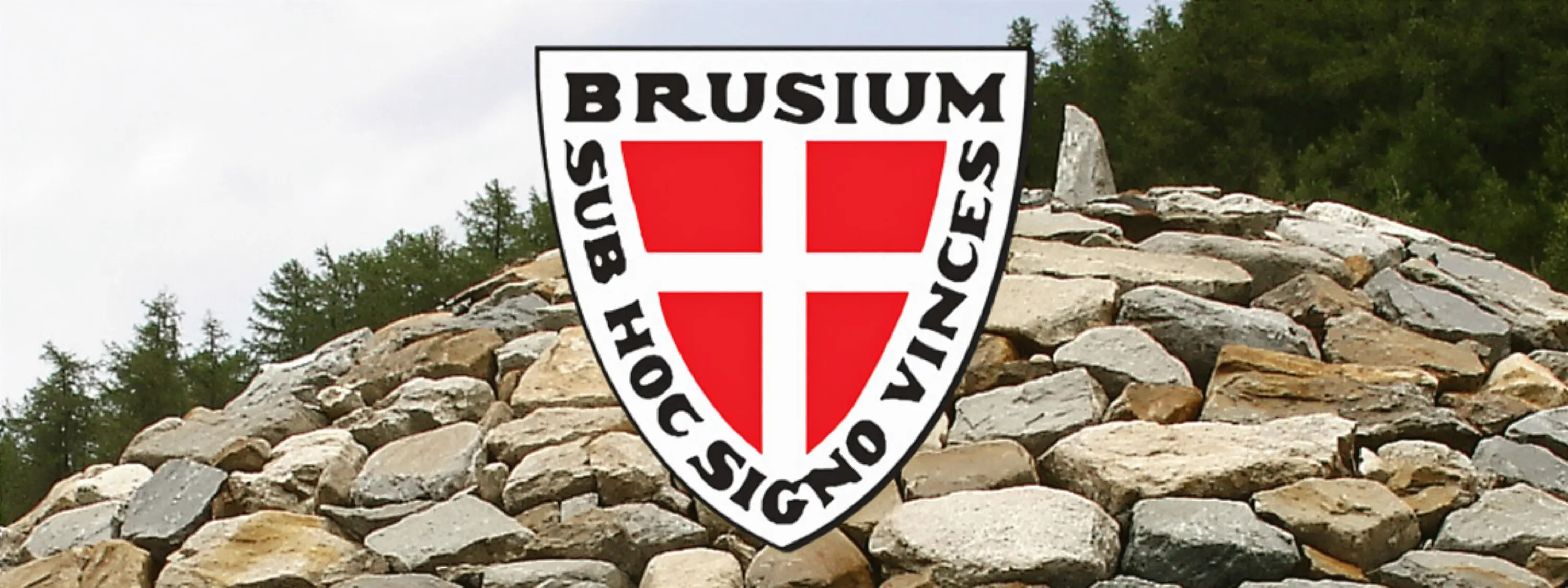 Scudetto con la scritta "BRUSIUM" e "SUB HOC SIGNO VINCES" su uno sfondo di pietre.