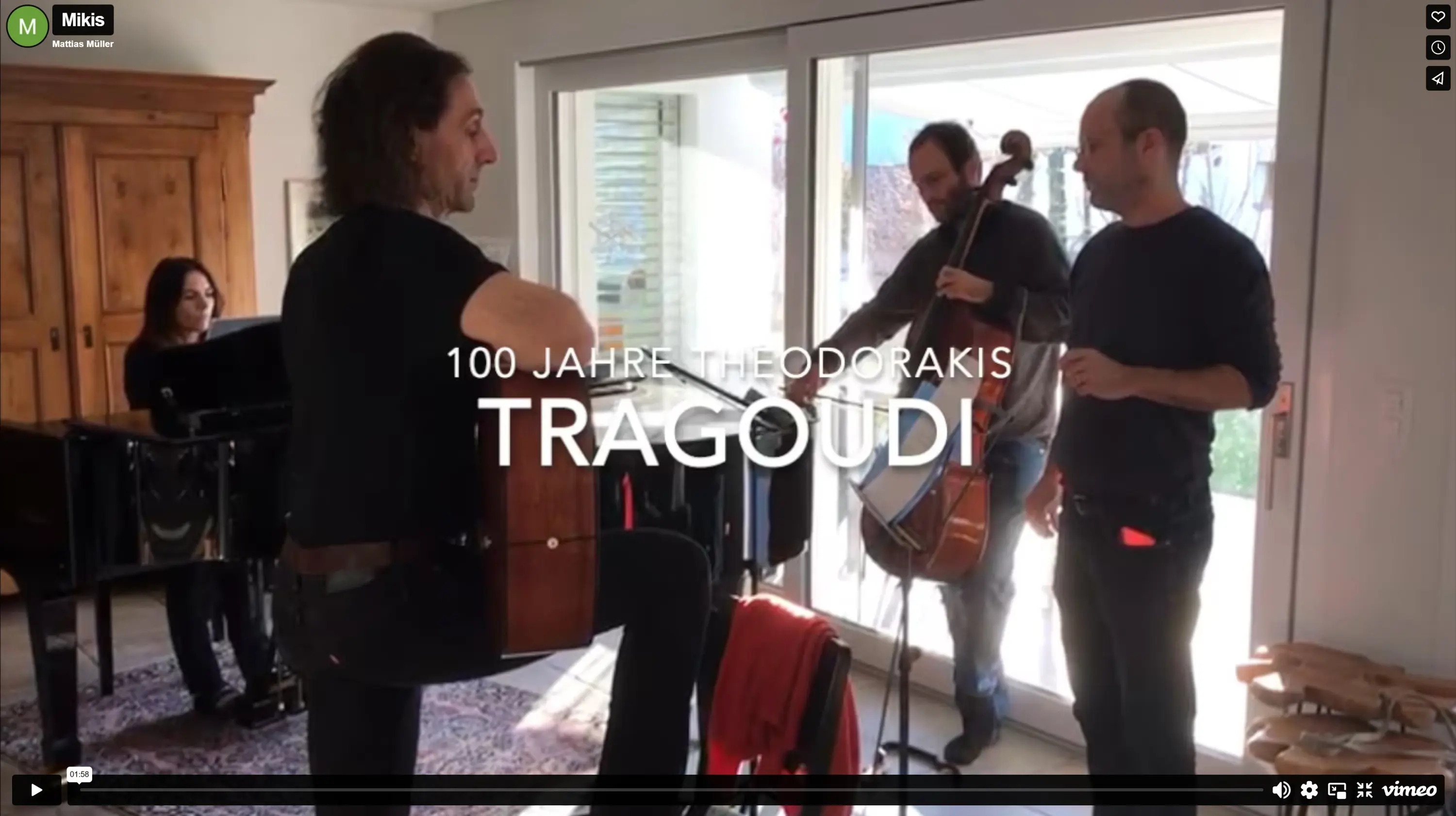 Un gruppo di musicisti si esibisce in una sala luminosa. Un uomo suona la chitarra, mentre un violoncellista e un pianista la osservano. La scritta "100 Jahre Theodorakis Tragoudi" è visibile al centro.