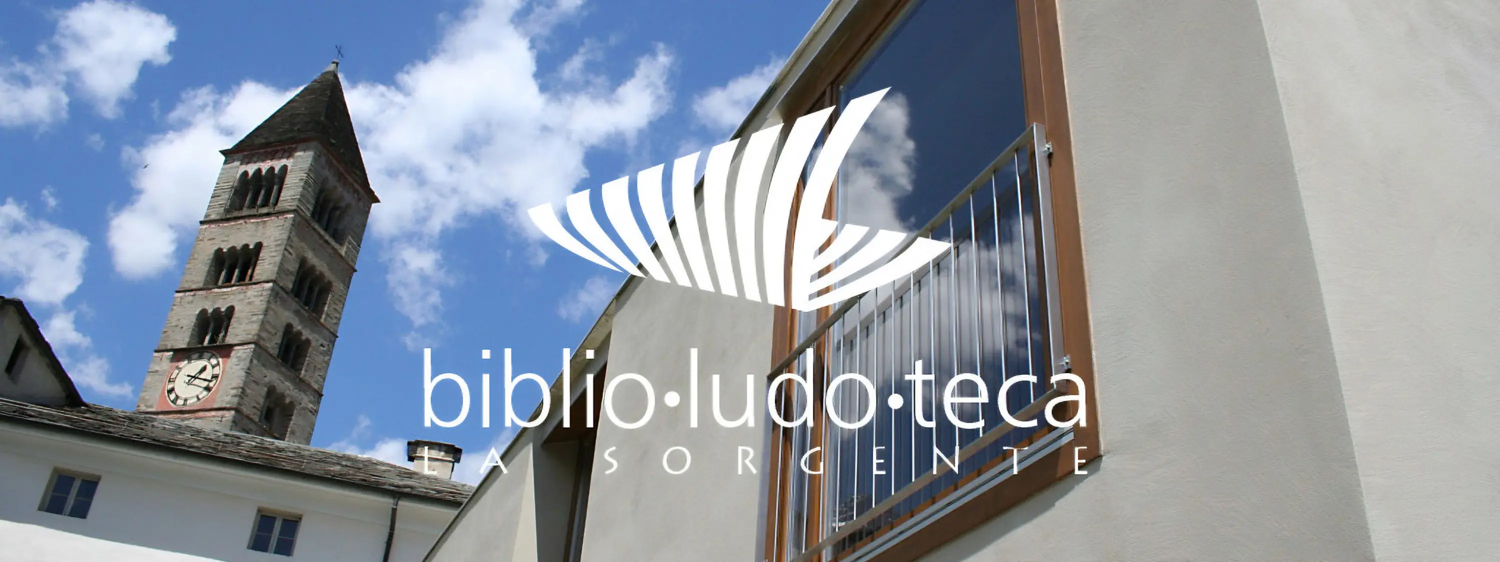 L'immagine mostra una torre con orologio e una facciata moderna di un edificio, con un cielo blu punteggiato di nuvole. Il logo "biblio:ludo:teca La Sorgente" è sovrapposto al design.