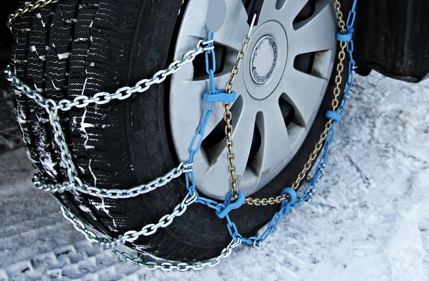 Catena da neve fissata a un pneumatico su una superficie innevata.