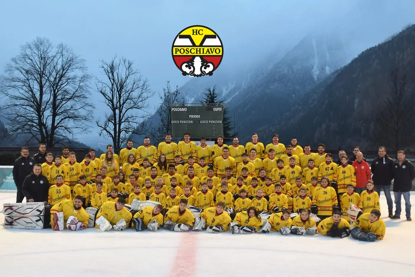 Gruppo di giocatori di hockey su ghiaccio dell'HC Poschiavo, tutti con divise gialle, posano insieme in un'area all'aperto con montagne sullo sfondo. Il logo dell'HC Poschiavo è visibile in cima all'immagine.