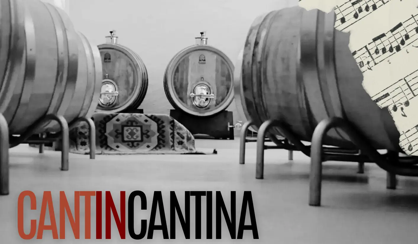 Un ambiente di cantina con grandi botti di legno e un tappeto sulla pavimentazione. Una parte della composizione include uno sfondo musicale. La parola "CANTIN" è
