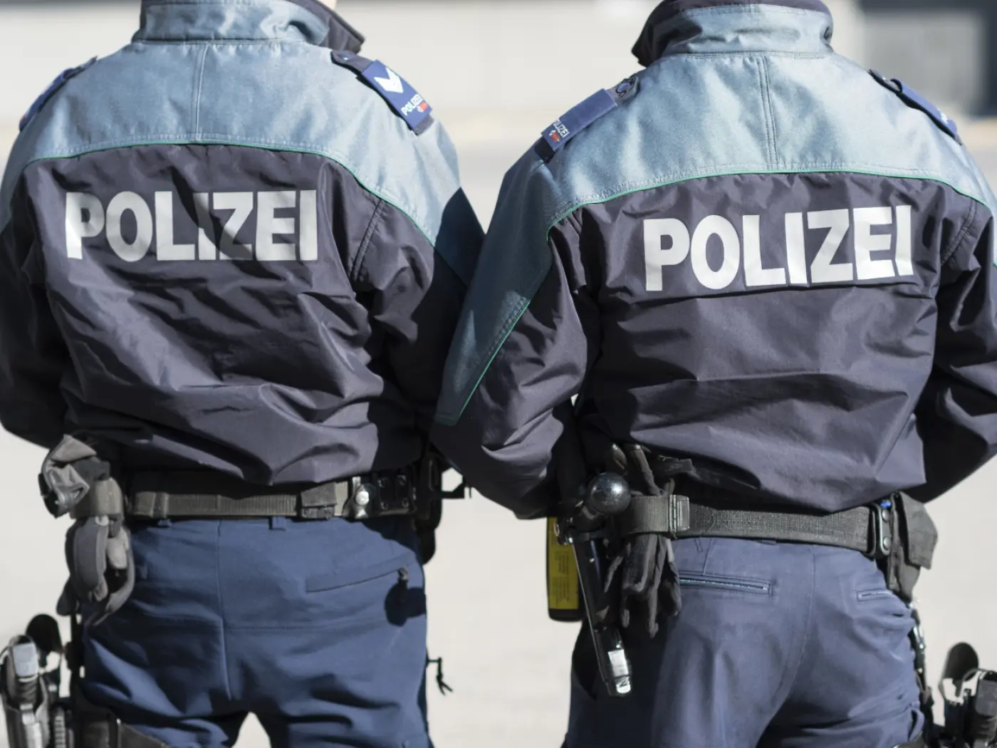 Due agenti di polizia in uniforme, visti di spalle, con la scritta "Polizei" su entrambe le giacche.